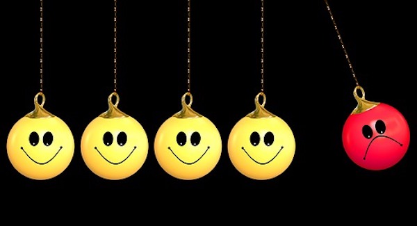 Bolas Emojis penduradas com caras felizes empurrando outra bola com cara triste, simbolizando a externalidade negativa