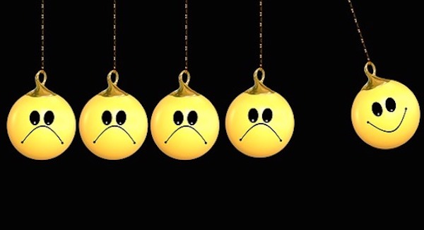 Bolas Emojis penduradas com caras tristes, empurrando outra bola com cara feliz, representando a externalidade positiva